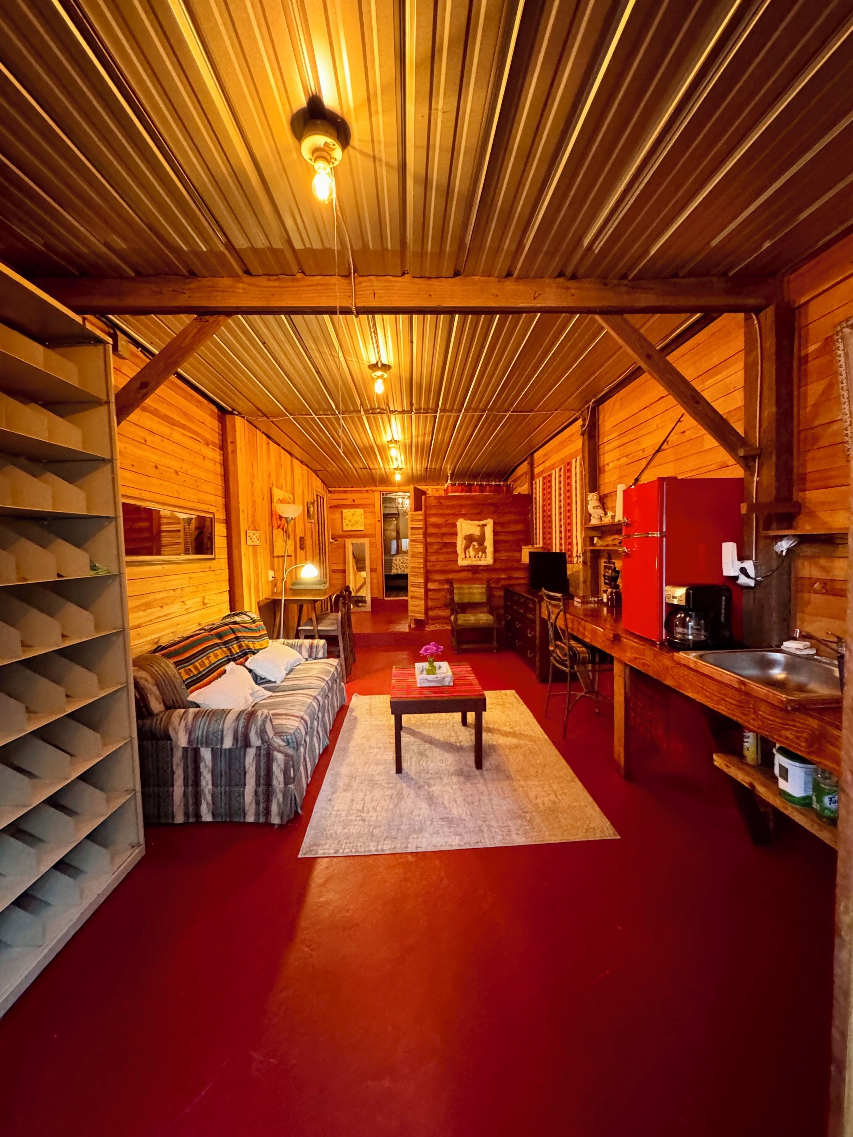 Interior acogedor de una cabaña con techo de madera, un sofá, una mesa de comedor y una zona de cocina.