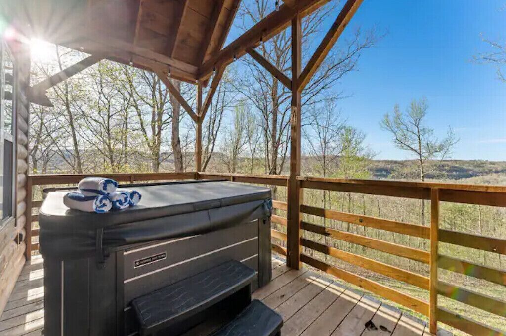 A hot tub on a wooden deck with a view of a mountainous landscape.