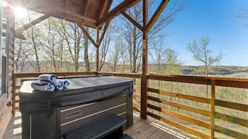 A hot tub on a wooden deck with a view of a mountainous landscape.