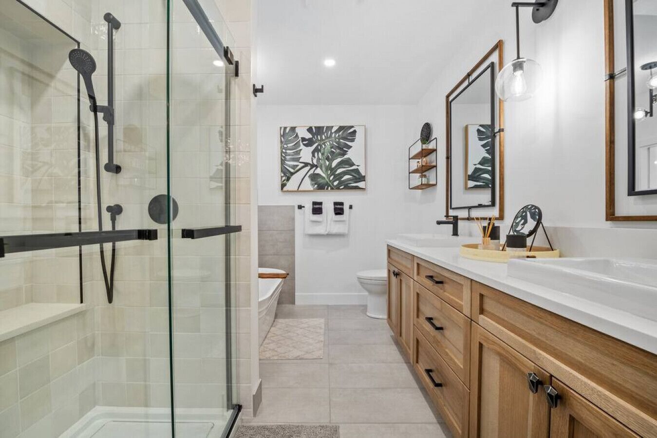 A modern bathroom with a glass shower enclosure, wooden cabinets, and a large mirror.