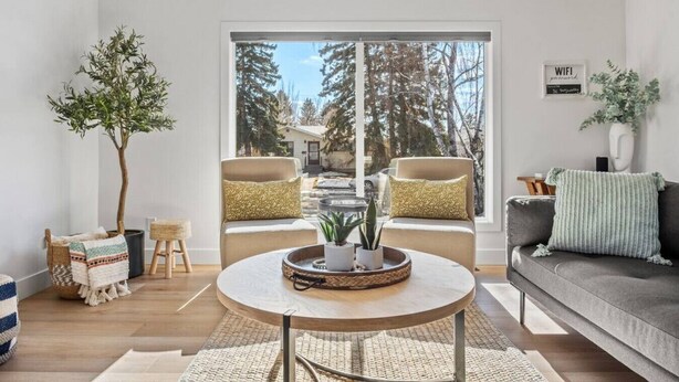 A modern living room with a large window, two sofas, a coffee table, and a potted plant. - The Duke | Spacious | Upscale | Close to DT (Calgary)