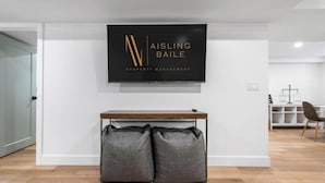 Un intérieur moderne avec un téléviseur à écran plat fixé au mur, qui affiche le logo « AISLING BAILE PROPERTY MANAGEMENT ».