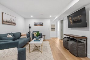 Ein modernes Wohnzimmer mit einer Couch, einem Couchtisch und einem an der Wand befestigten Fernseher.