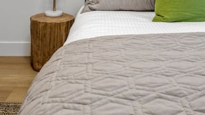 Une chambre à coucher avec un lit, une table de chevet, une lampe et un tableau au mur.