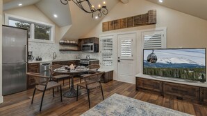 A modern kitchen with a dining area, wooden flooring, and a large TV displaying a mountain view. - Downtown Home + Mtn Views + Hot Tub + Ski Shuttle - Lansdowne Chateau (Breckenridge)
