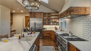 A modern kitchen with a central island, stainless steel appliances, wooden cabinets, and a large window. - Downtown Home + Mtn Views + Hot Tub + Ski Shuttle - Lansdowne Chateau (Breckenridge)
