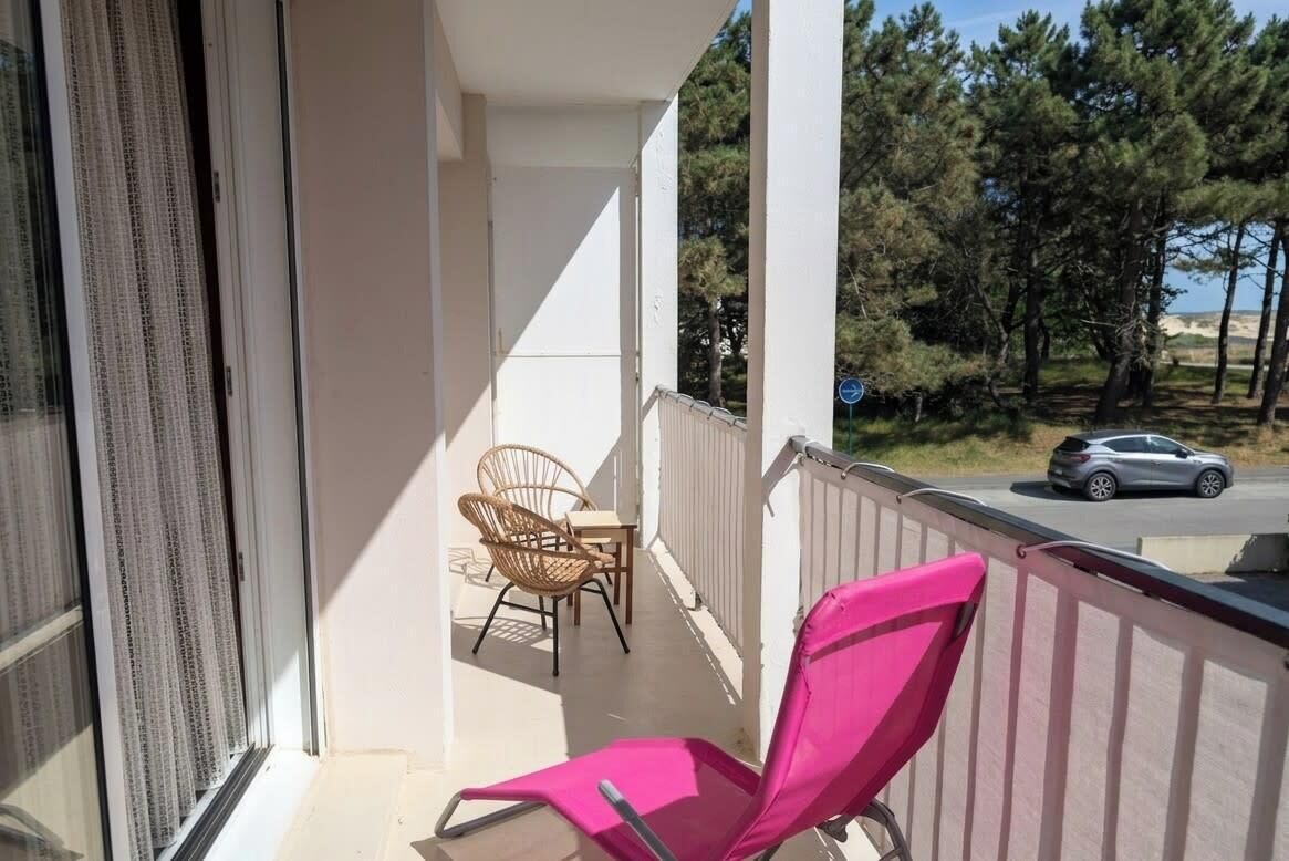 Ein Balkon mit Stuhl, Tisch und Blick auf eine Straße und Bäume.
