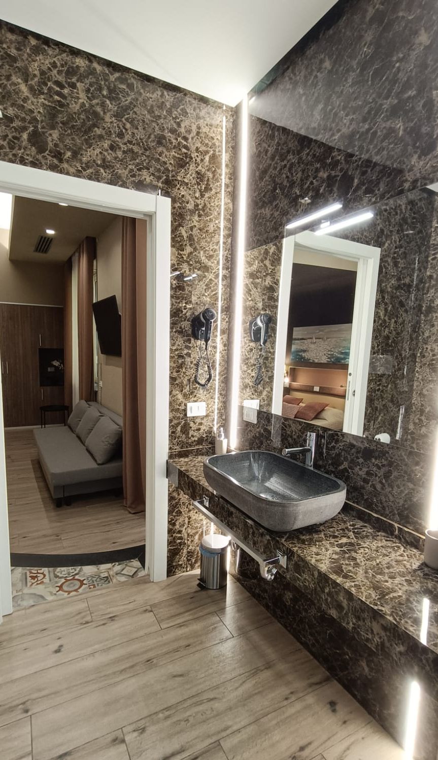 Un baño con un espejo grande, un lavamanos integrado y una zona de ducha.