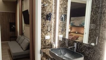 Un baño con un espejo grande, un lavamanos integrado y una zona de ducha.