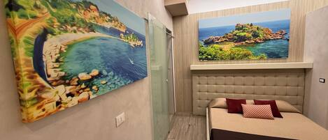 Un dormitorio con cama, un cuadro grande en la pared y una ventana con vistas al mar.