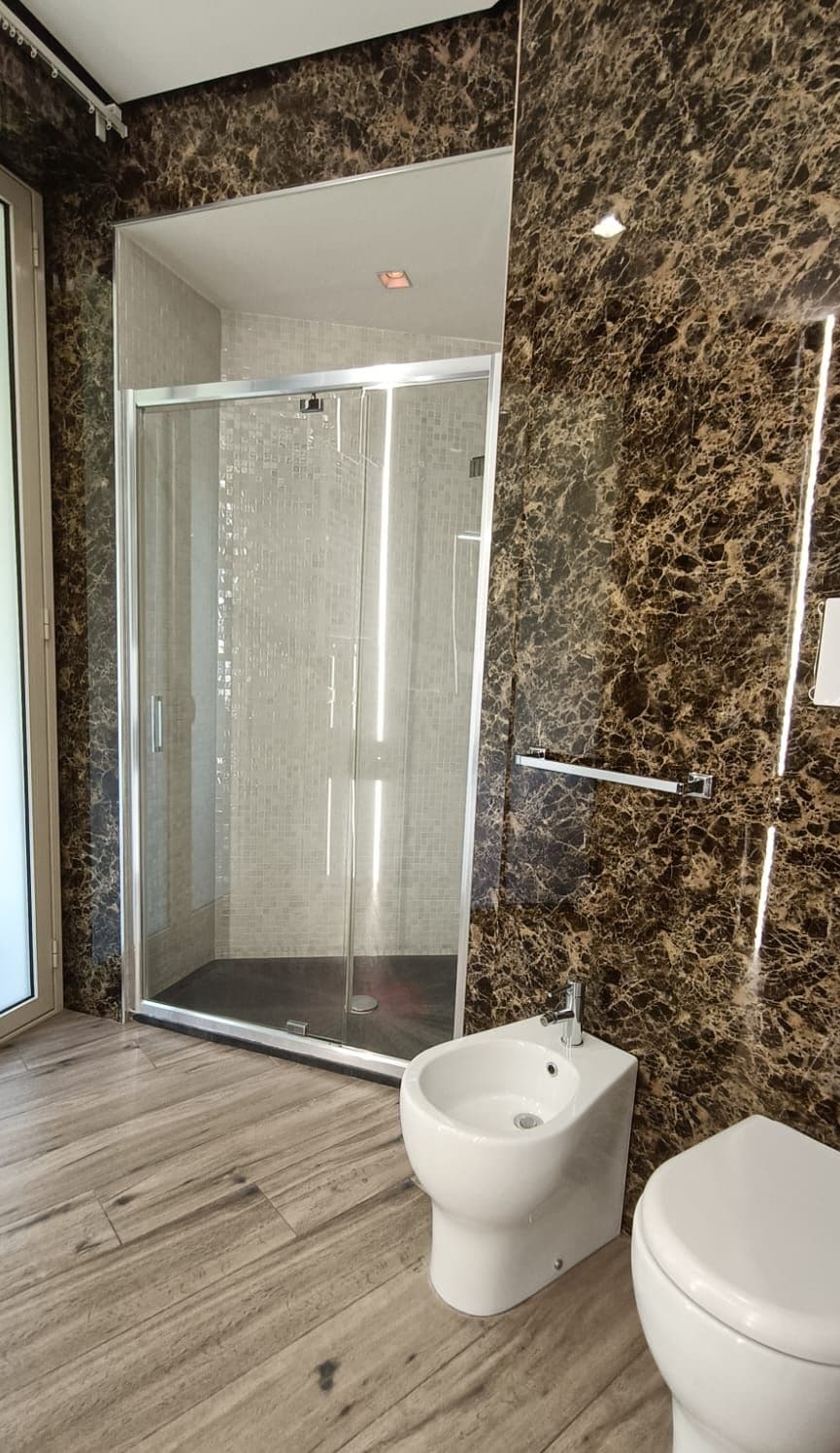 Een moderne badkamer met een douchecabine van glas, een bidet en een toilet.