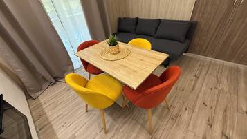 A dining area with a wooden table, yellow and red chairs, and a grey sofa.