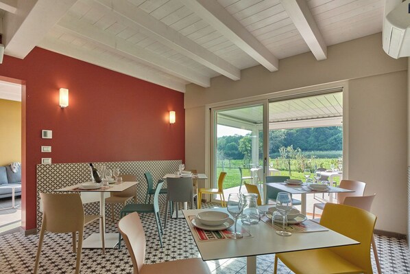 A dining area with a table set for two, a patterned backsplash, and a view of a garden through large windows.