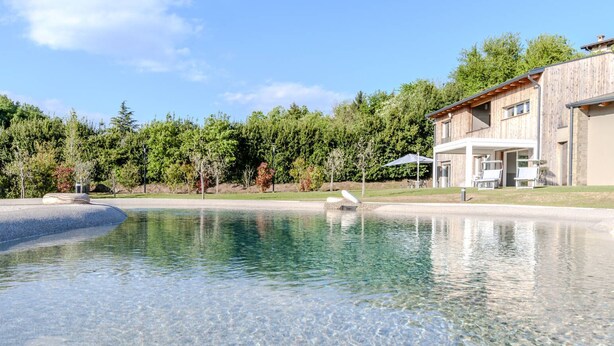 A clear swimming pool with a wooden house in the background. - Melograno Apartment - Poggio le Crete (Soiano)