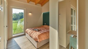 A bedroom with a bed, a door, a window, and a view of the outdoors. - Melograno Apartment - Poggio le Crete (Soiano)