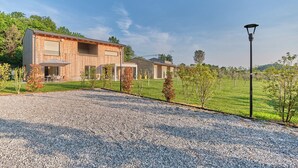 A modern house with a gravel driveway, a covered patio, and a street lamp. - Melograno Apartment - Poggio le Crete (Soiano)