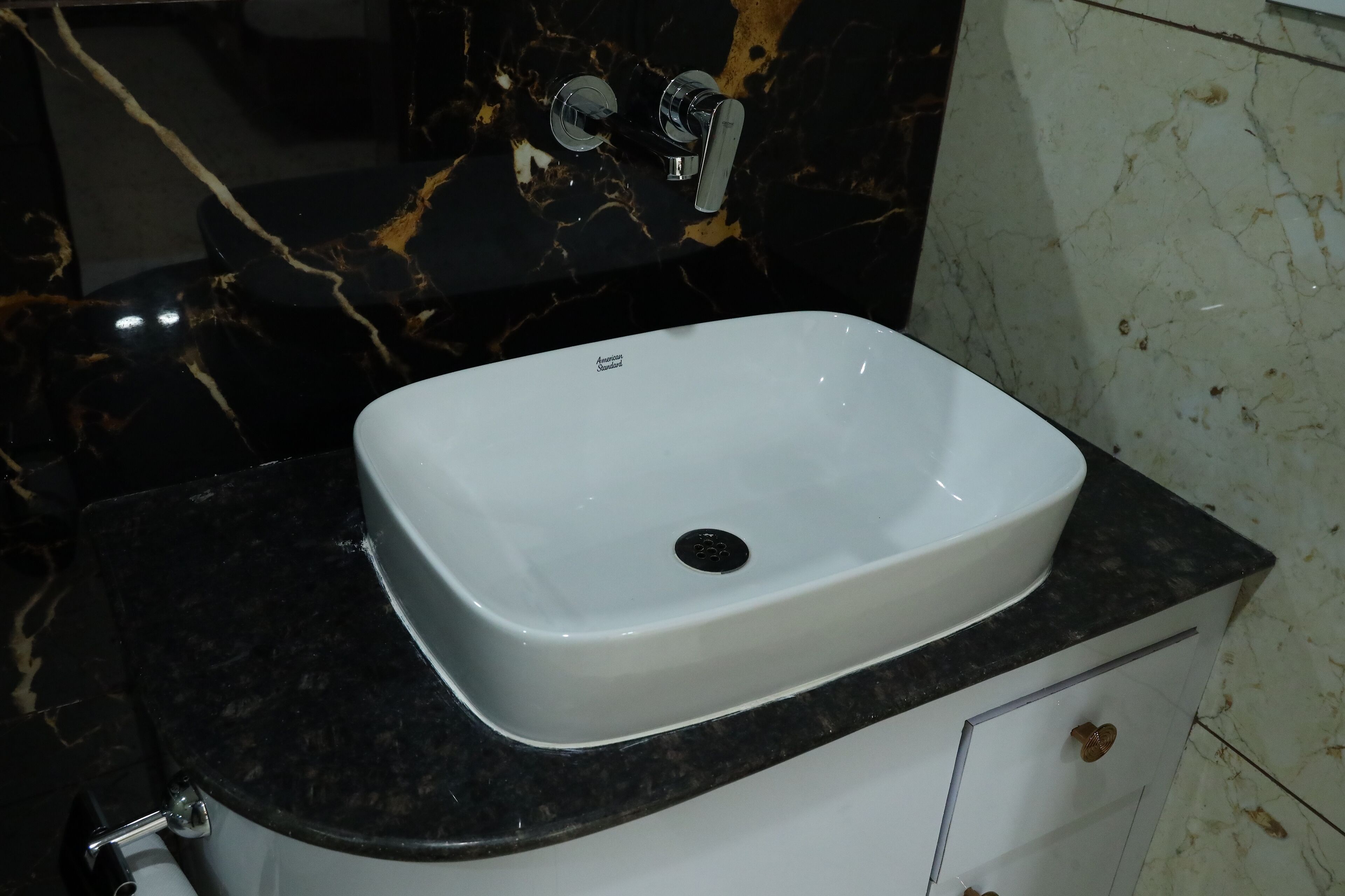A bathroom with a white sink, black marble countertop, and a mirror above the sink.