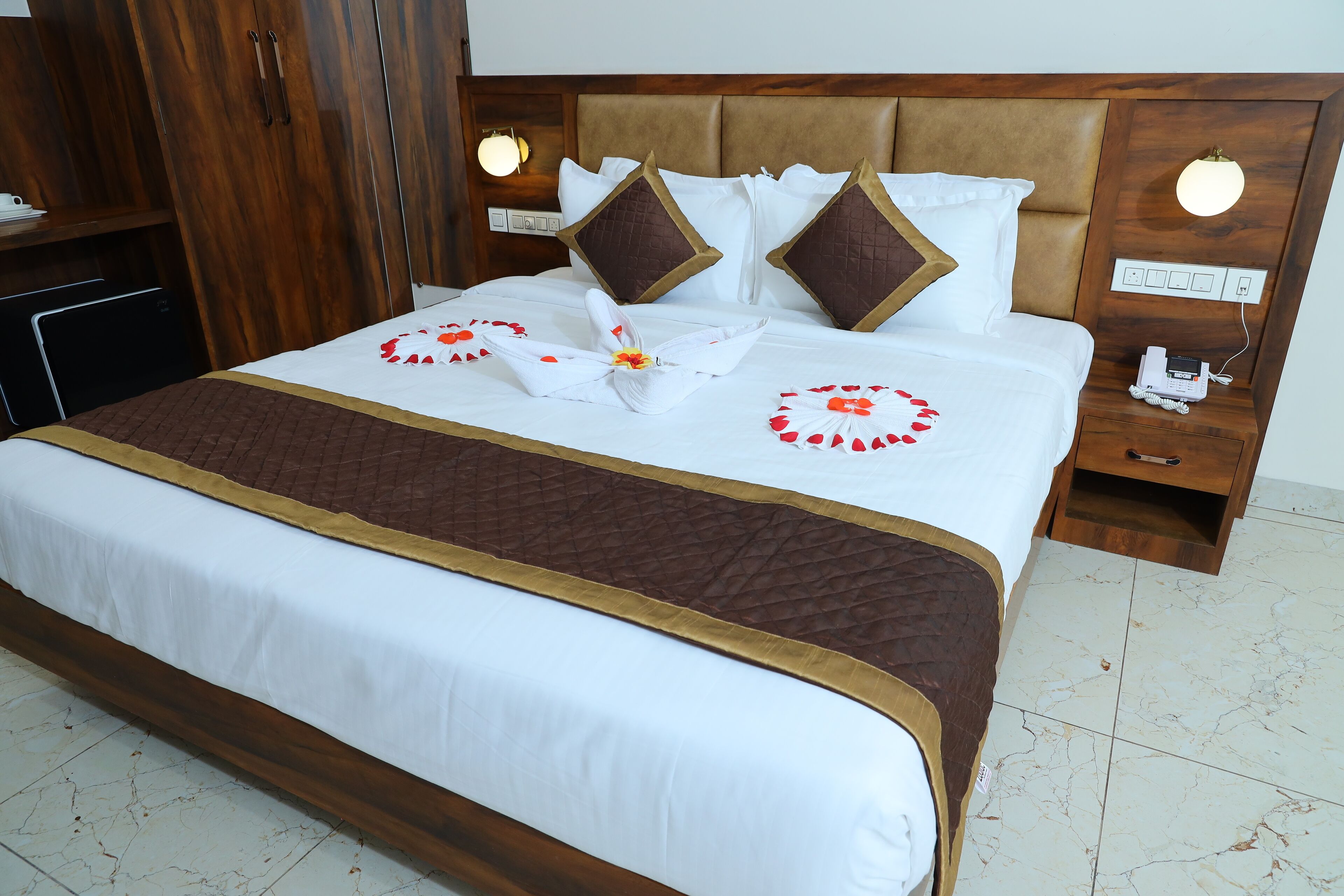 Cama bem arrumada com colcha marrom, roupa de cama branca e almofadas decorativas.