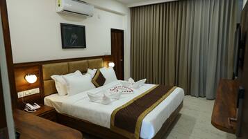 A neatly made bed with white linens, a brown headboard, and a brown accent strip. There is a wall-mounted air conditioner and a framed picture above the bed.