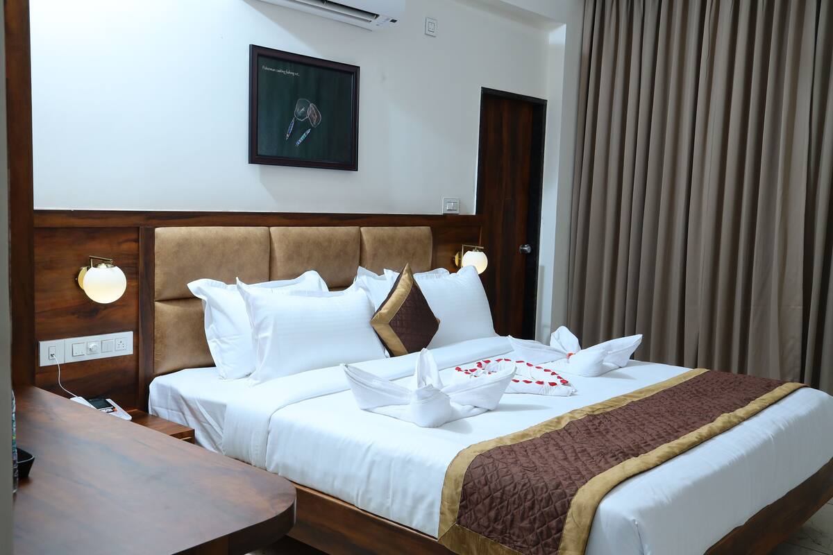 A hotel room with a bed, bedside table, wall-mounted lamp, and a framed picture.