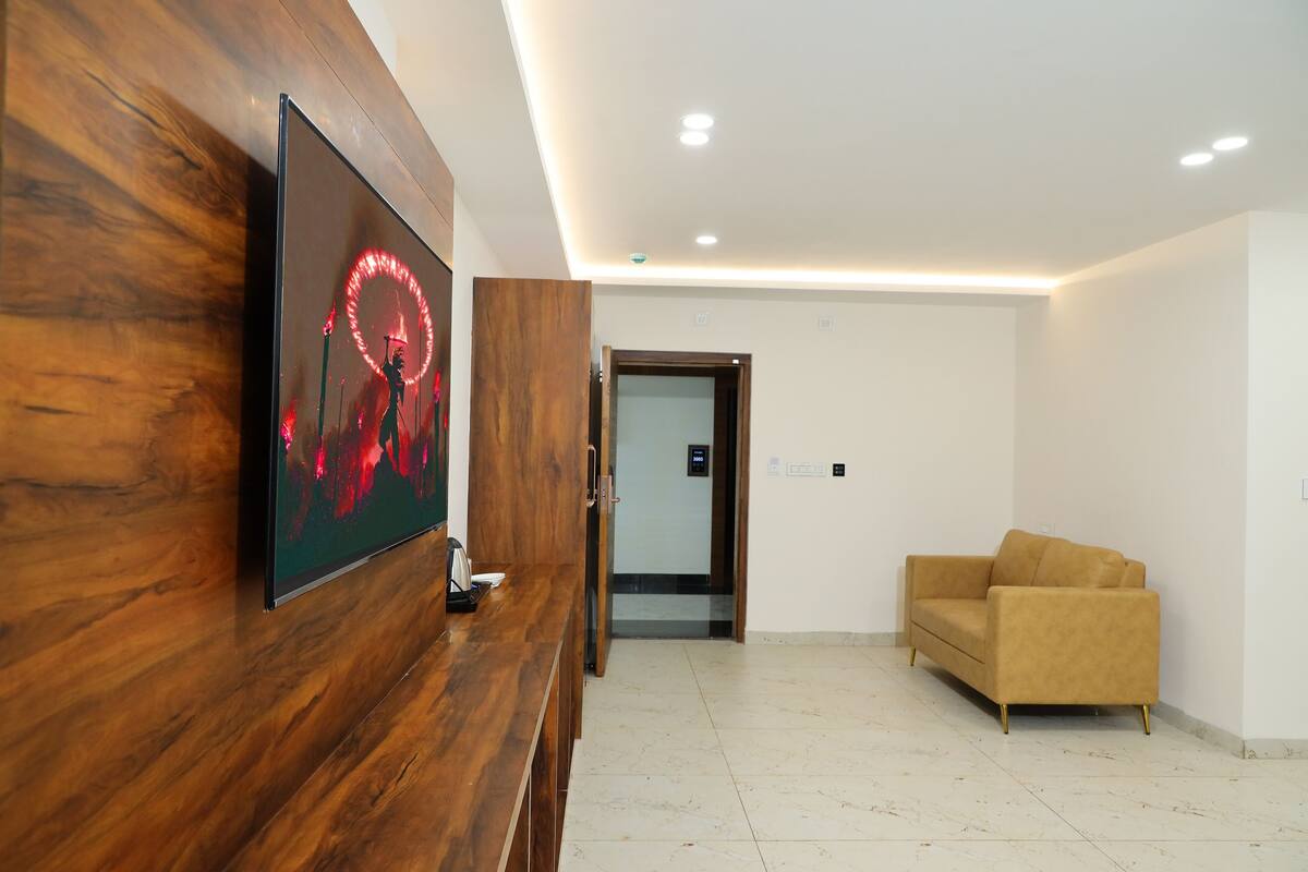 A reception area with a wooden reception desk, a framed artwork, a sofa, and a door leading to another room.