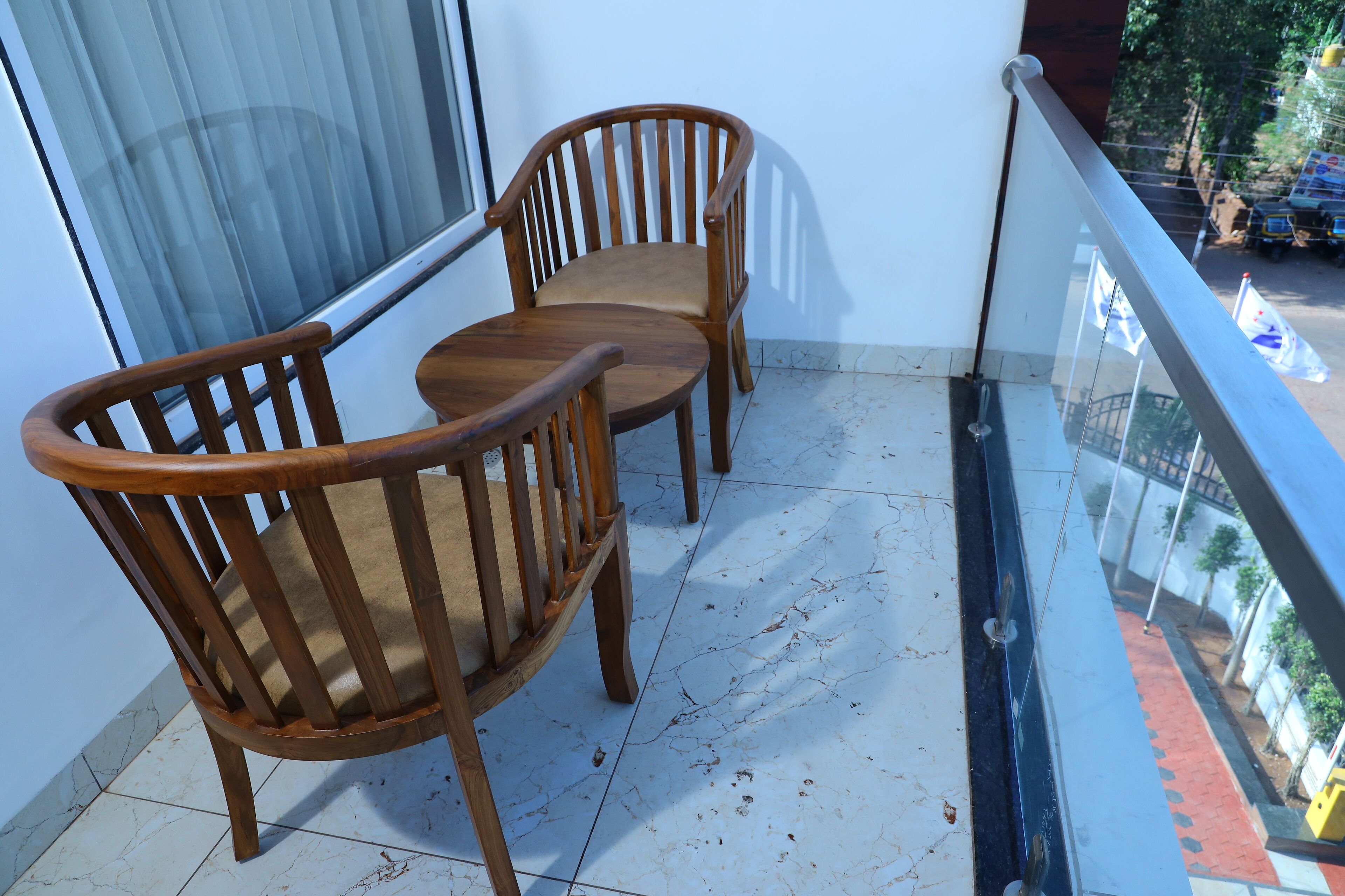 A balcony with two wooden chairs and a glass railing.