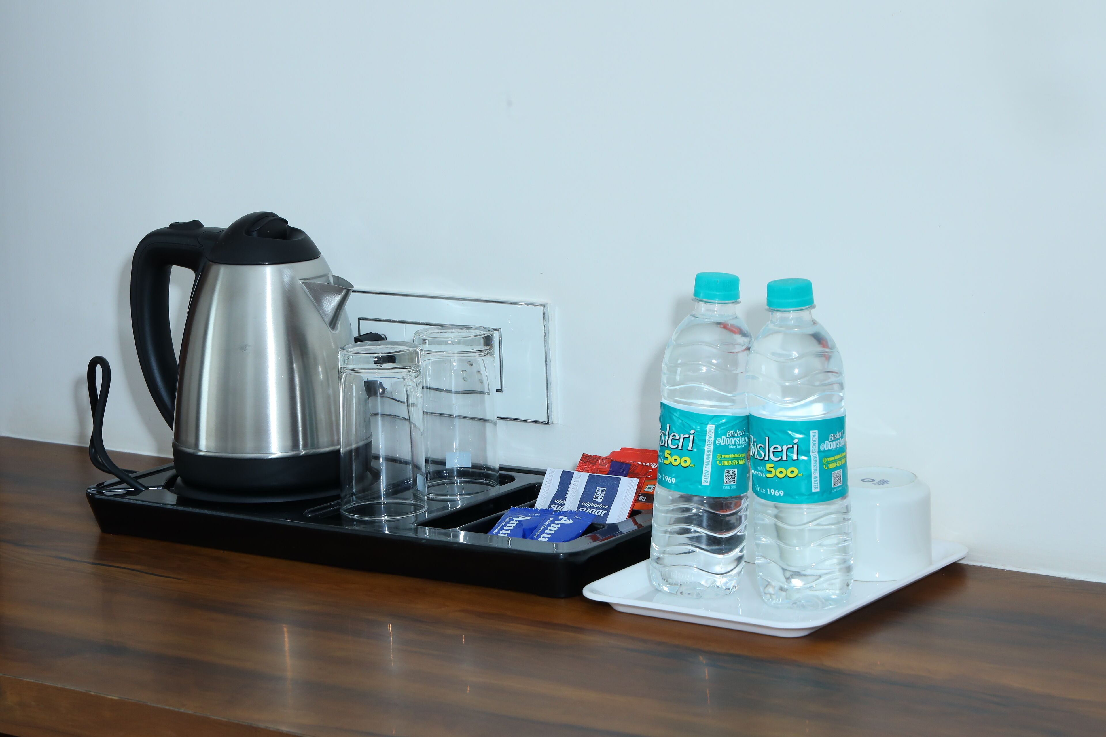 A coffee maker, two water bottles, and a tray with a few items on a wooden table.