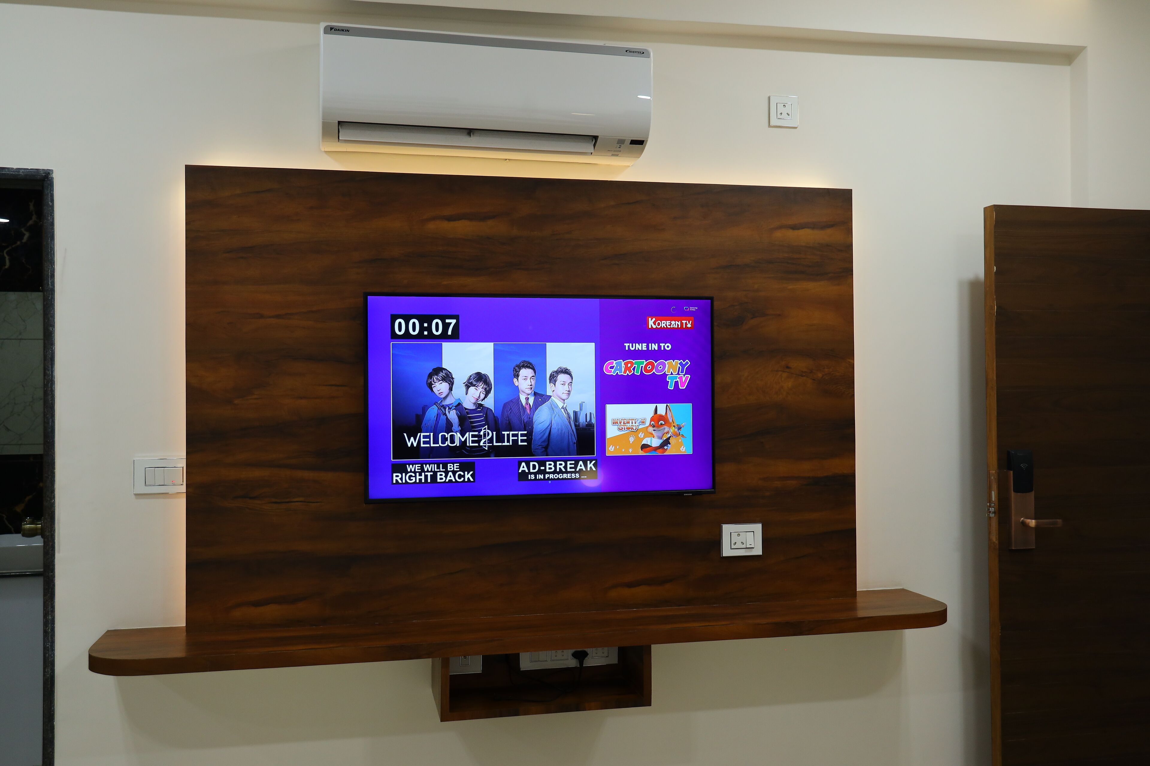 A television mounted on a wooden wall with a digital display showing a cartoon TV channel.