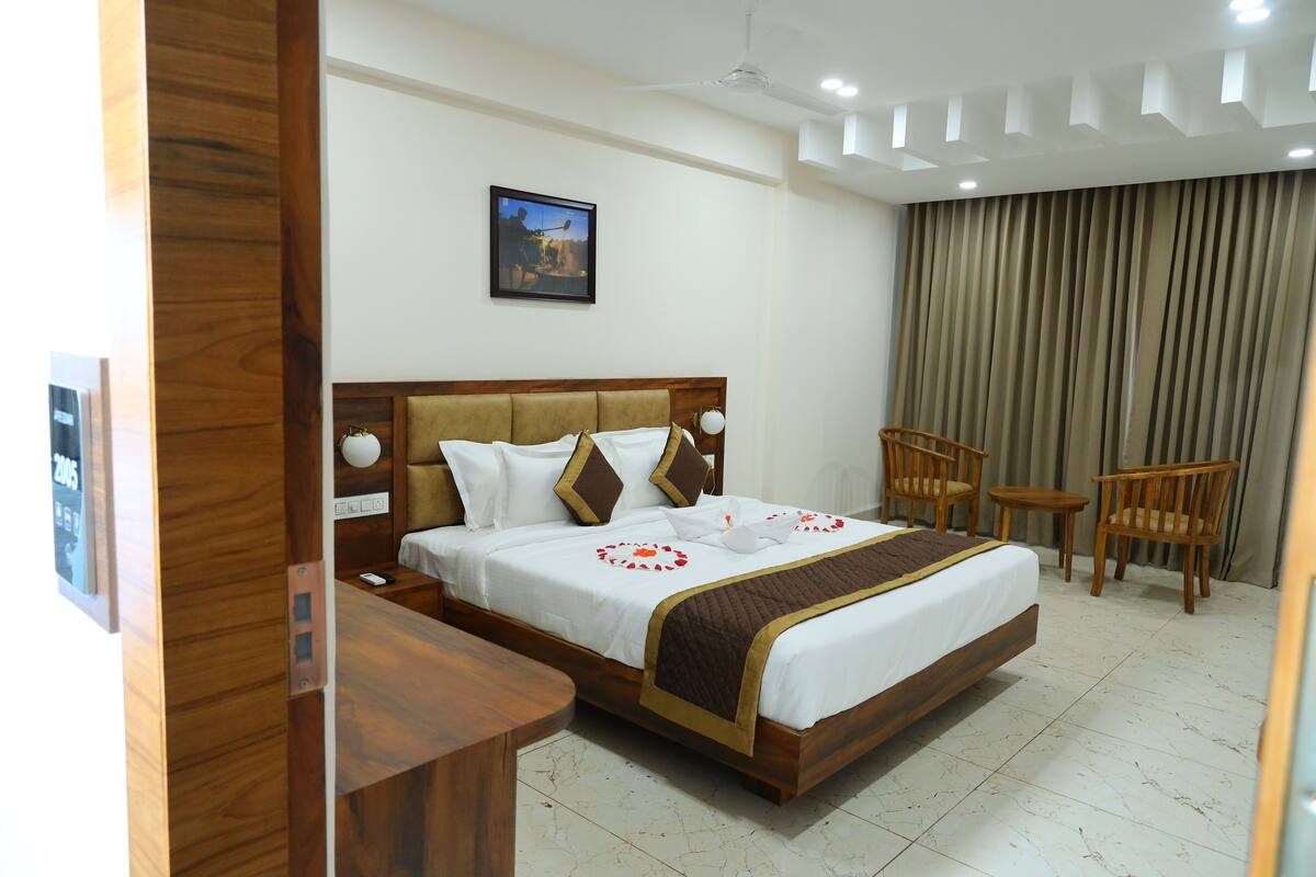 A hotel room with a large bed, wooden headboard, two bedside tables, a desk, and a chair.