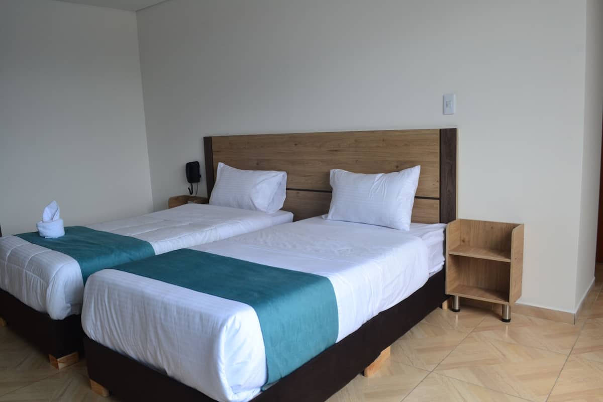 A double bed with a wooden headboard, two pillows, and a teal throw blanket.