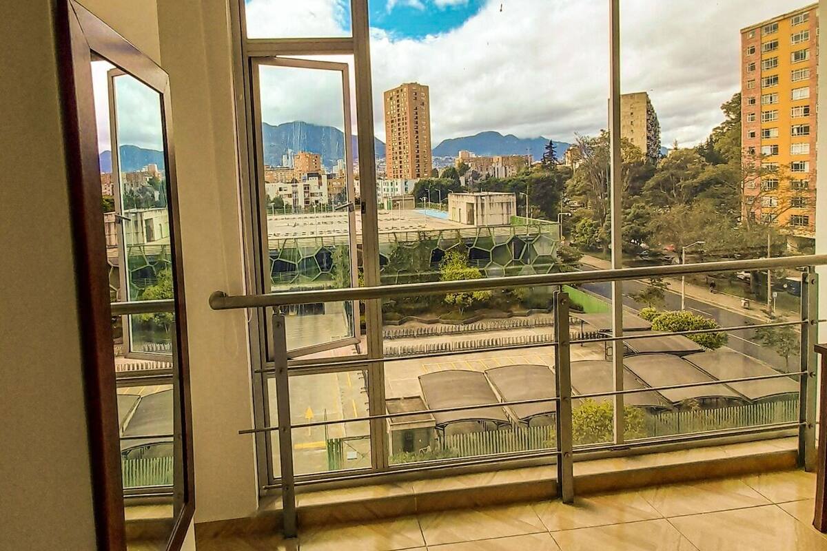A room with large windows offering a view of a cityscape, including buildings and a road.