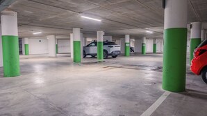 Un aparcamiento de varios niveles con pilares de hormigón y un coche blanco estacionado en una de las plazas.