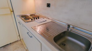 Una cucina con piano cottura, lavello e pensili bianchi.