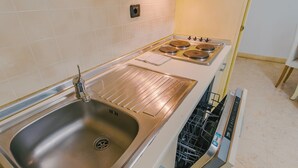 A kitchen with a stainless steel sink, a dishwasher, and a stove with four burners.