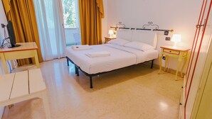 A neatly arranged hotel room with a bed, bedside tables, a chair, and a desk.