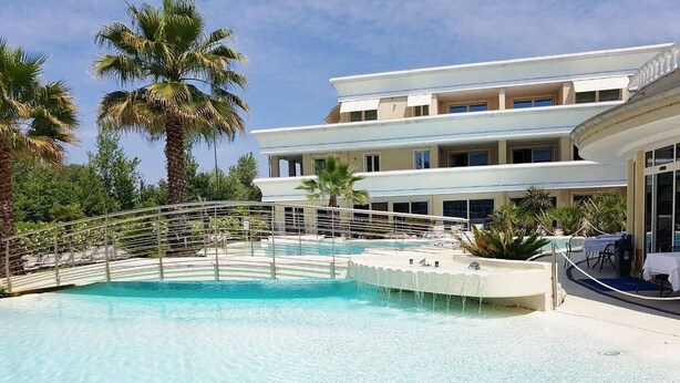 A resort pool with a palm tree and a building in the background.