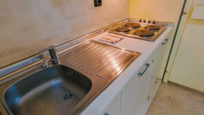 A kitchen with a stainless steel sink, a stove with four burners, and a white countertop.