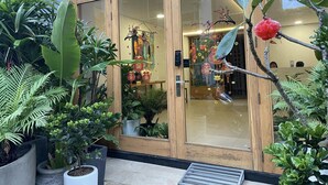 A hotel entrance with a wooden facade, glass doors, and a variety of potted plants. - Can ho cach bien My Khe 350m RentalFM2 (Da Nang)