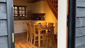 A cozy kitchen with wooden cabinets, a dining table with chairs, and a staircase leading to an upper level. - Two Storey Annex (Cambridge)
