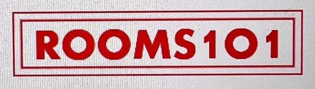 Un letrero con el texto 'ROOMS 101' en letras rojas y llamativas sobre fondo blanco.