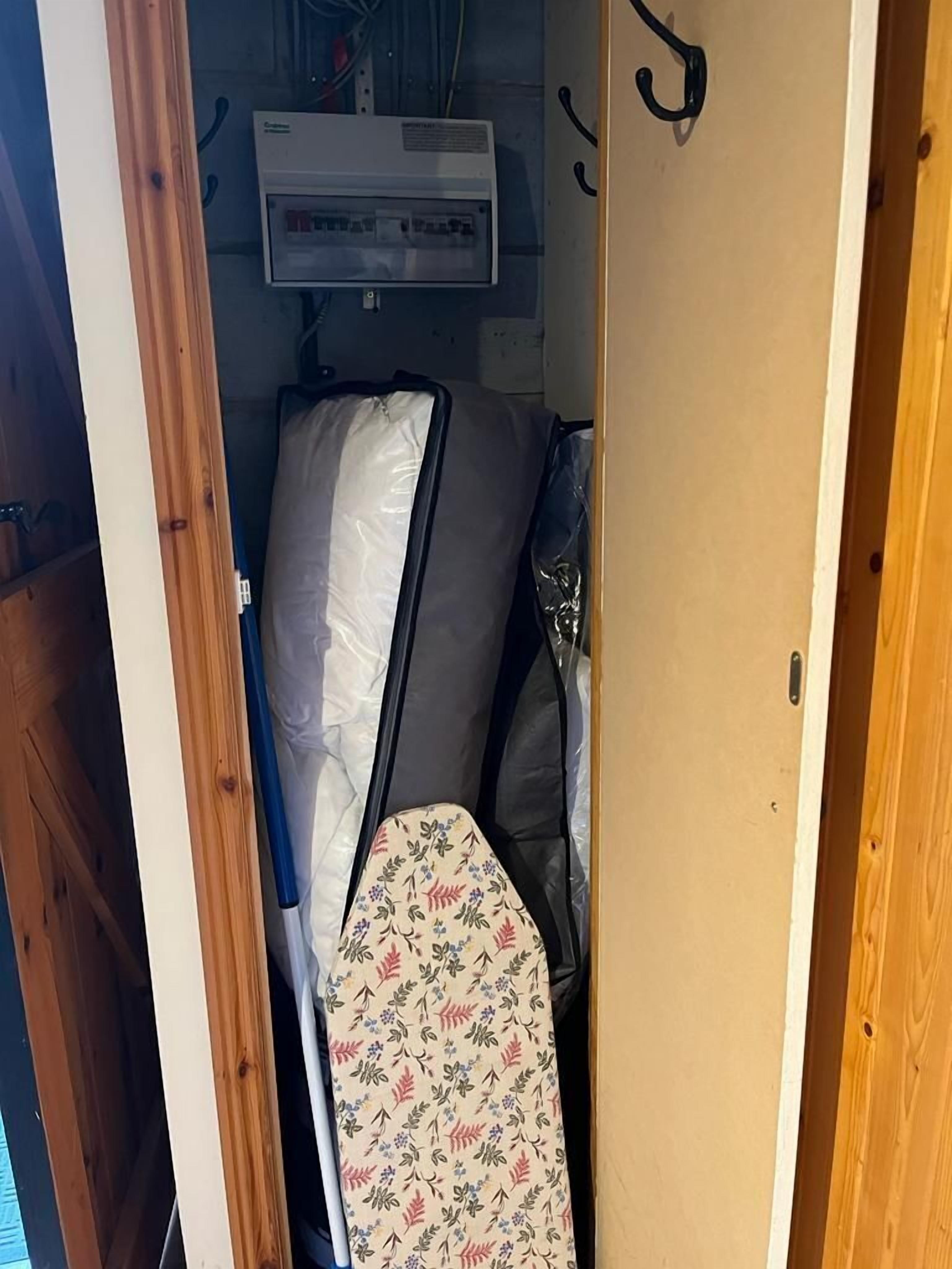 A compact room with a bed, a mattress, and a power outlet on the wall.