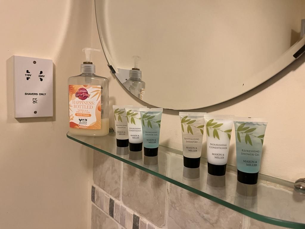 A bathroom shelf with various personal care products, including a bottle of lotion and several tubes of shampoo and conditioner.