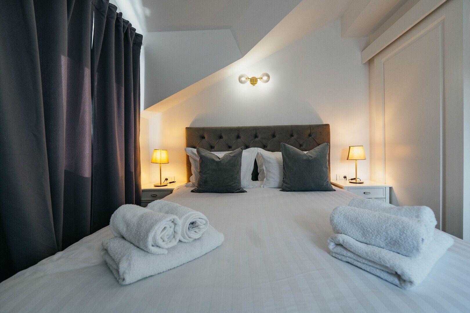 Una habitación de hotel con una cama grande, dos lámparas de noche y un cabecero.