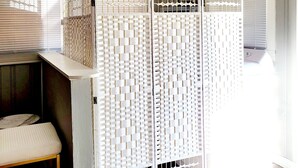 A room with a white partition, a wooden bench, and a window with blinds.