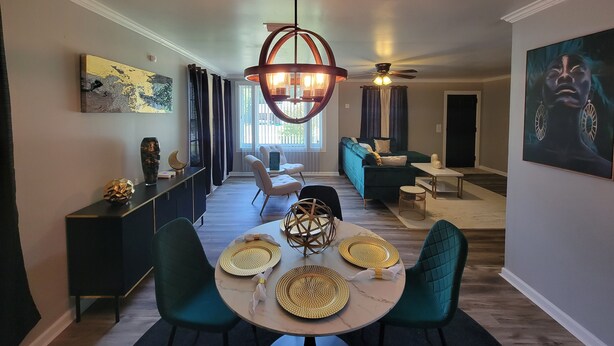 A modern dining area with a round table, chairs, and a ceiling fan.