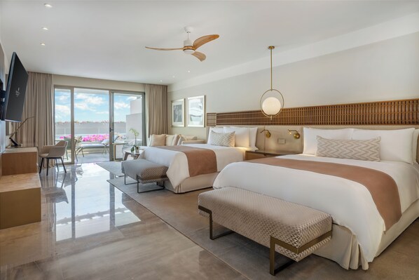 A modern hotel room with two beds, a ceiling fan, a TV, and a balcony with pink flowers. - Grand Velas Boutique Hotel - Adults Only - All Inclusive (Cabo San Lucas)