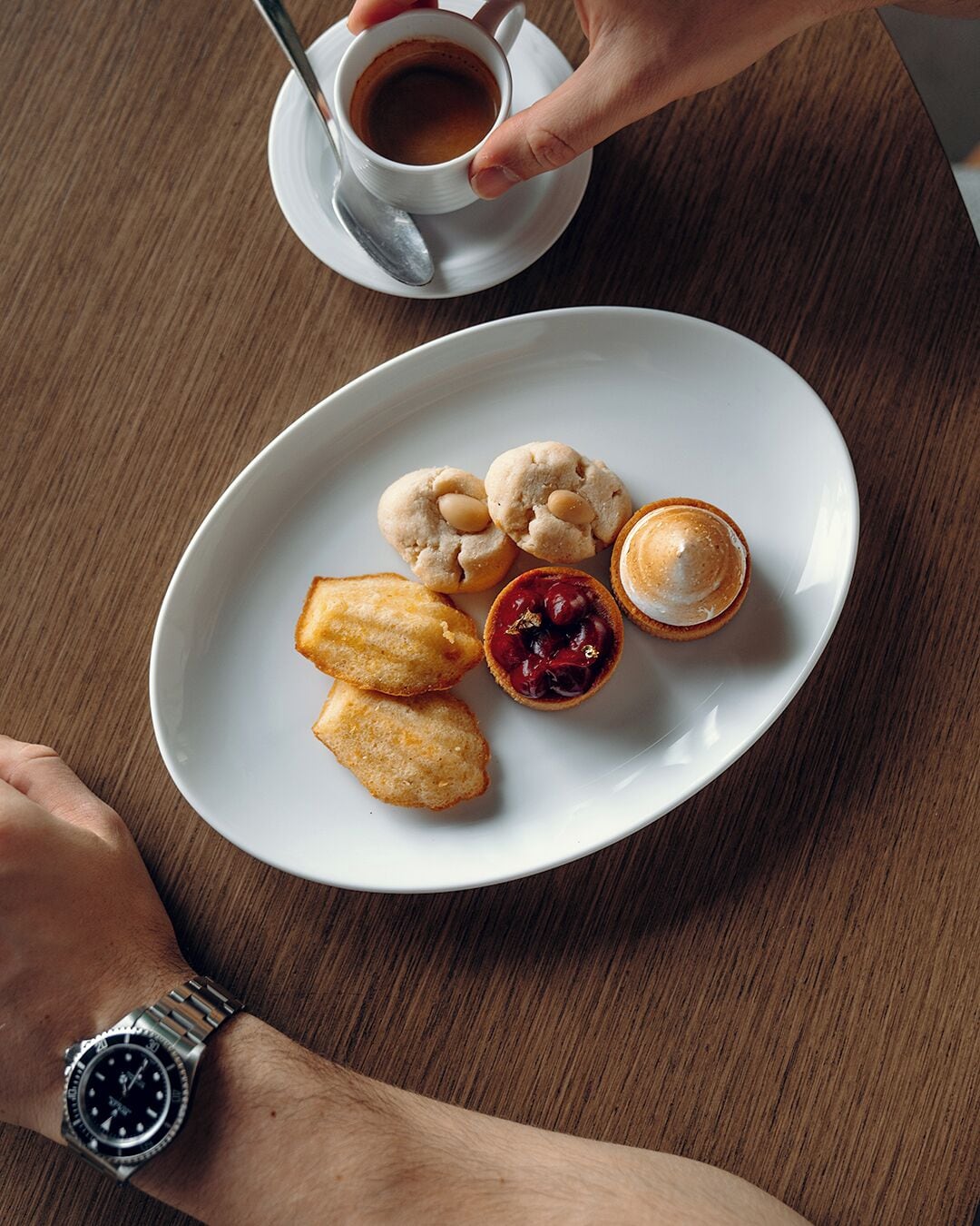 A plate with pastries and a cup of coffee on a wooden table.