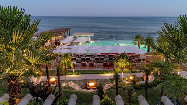 Un resort con piscina, sillas de descanso y palmeras.
