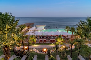 A resort with a pool, lounge chairs, and palm trees. - Grand Velas Boutique Hotel - Adults Only - All Inclusive (Cabo San Lucas)