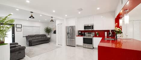 Una cocina moderna con armarios blancos, electrodomésticos de acero inoxidable y encimera roja.